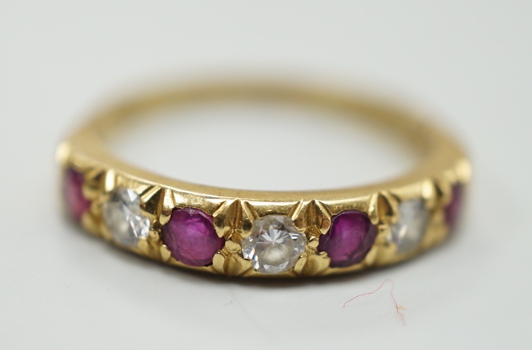 A modern 18ct gold, four stone ruby and three stone diamond set half hoop ring, size L/M